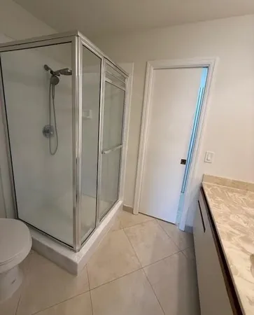 a bathroom with a granite countertop shower and a toilet