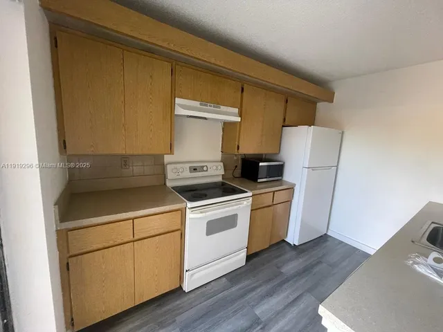 a kitchen with a stove top oven and refrigerator
