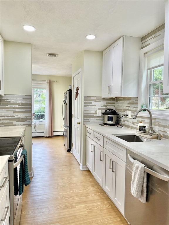 25 Homeward Lane, Unit 25 Natick, MA 01760 - Photo 5 of 16 a kitchen with stainless steel appliances granite countertop a stove top oven a sink a refrigerator white cabinets and wooden floor