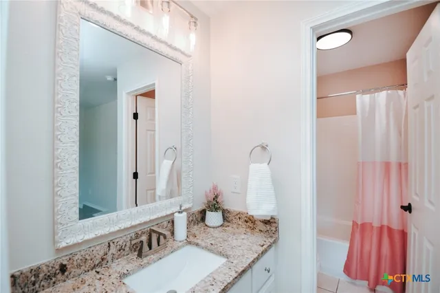 a bathroom with a granite countertop sink a mirror and shower