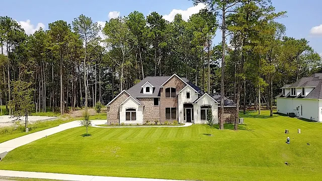 a view of a white house with a big yard and large trees