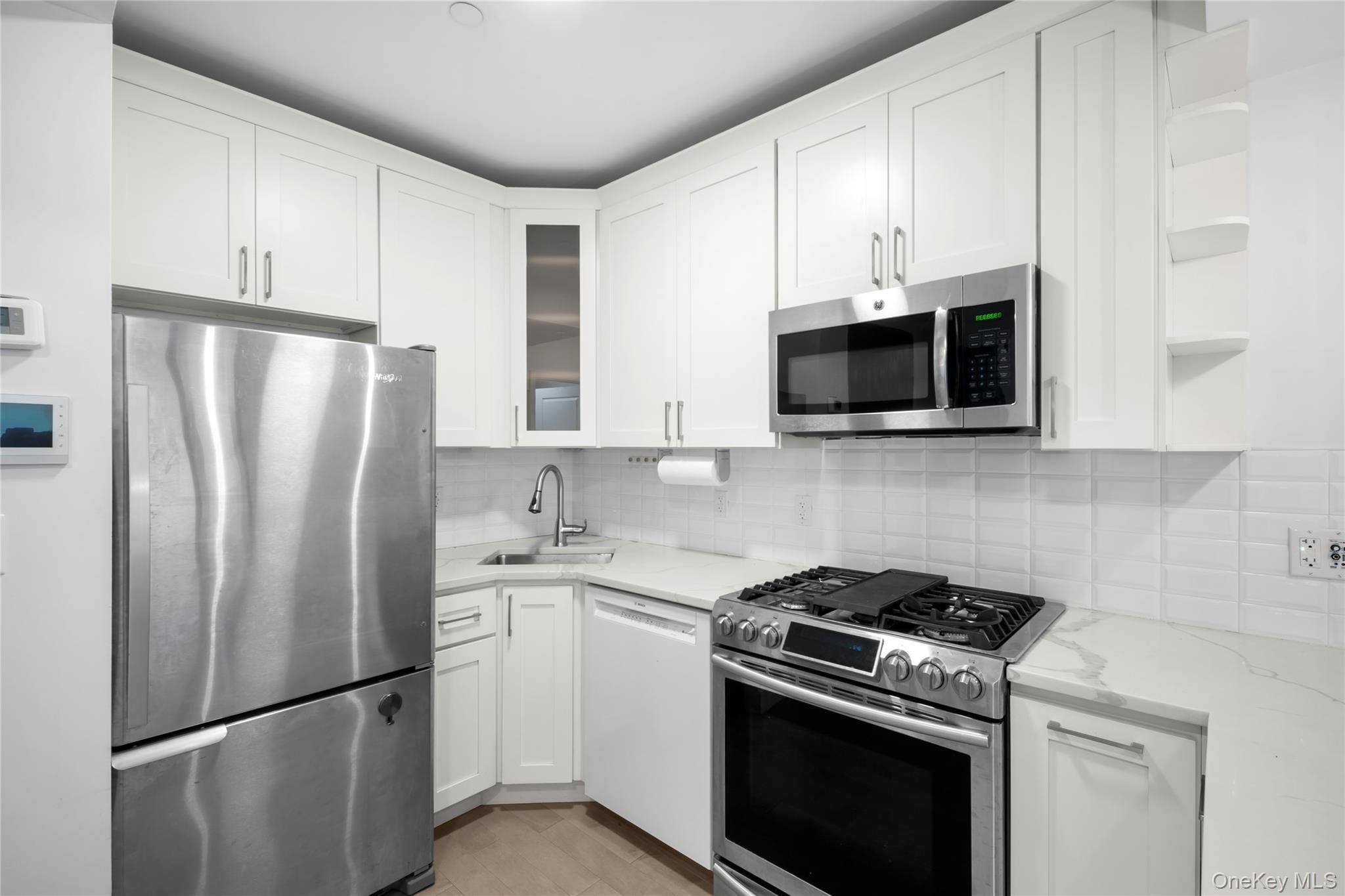 41-04 27th Street, Unit 7A Queens, NY 11101 - Photo 6 of 17 a kitchen with stainless steel appliances a refrigerator stove and microwave