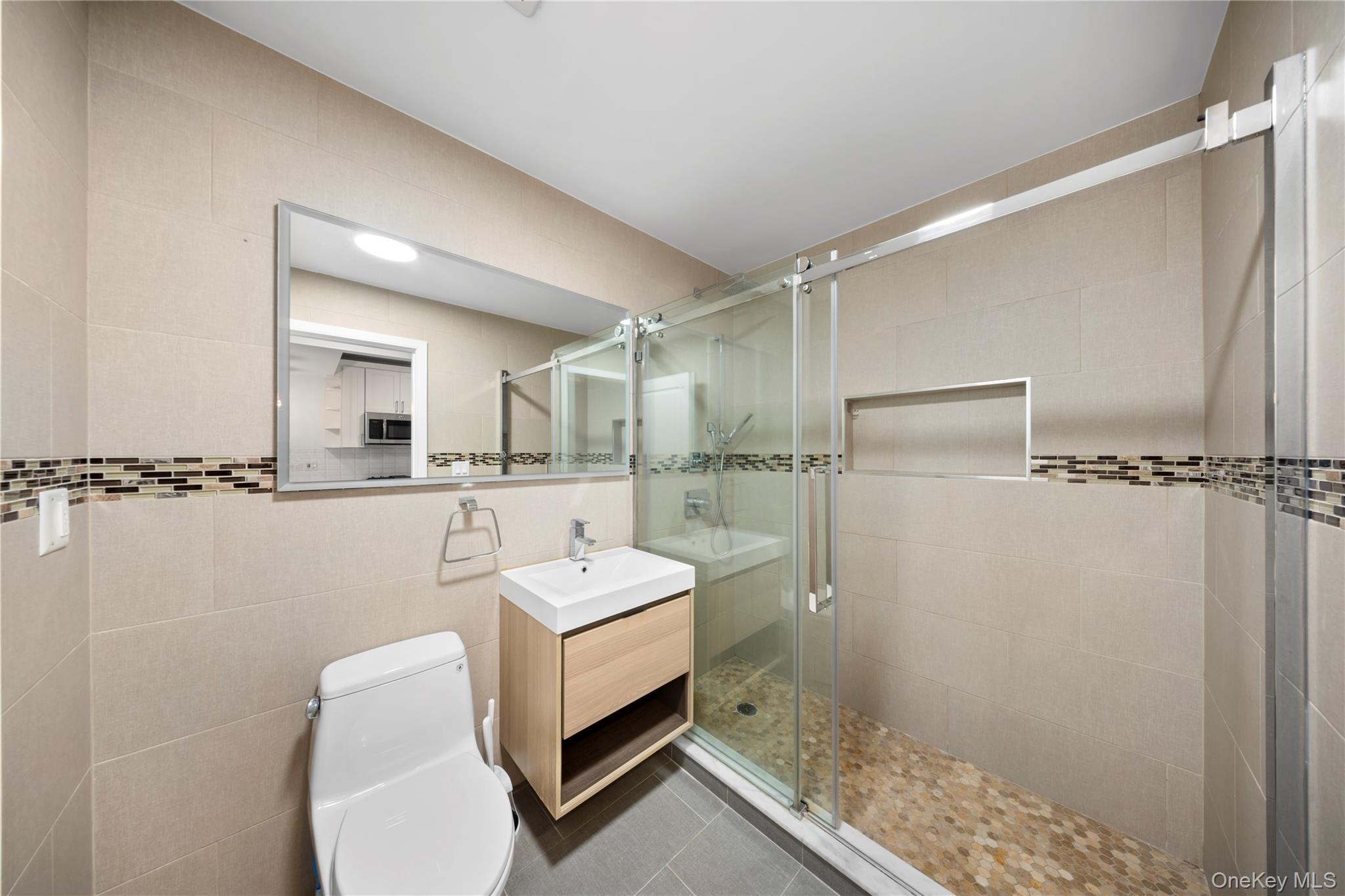 41-04 27th Street, Unit 7A Queens, NY 11101 - Photo 10 of 17 a bathroom with a toilet a sink and mirror