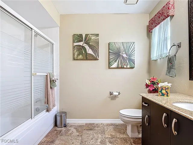 a bathroom with a granite countertop sink a toilet and shower