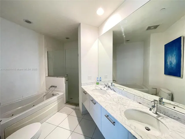 a bathroom with a granite countertop double vanity sink a mirror and a bathtub