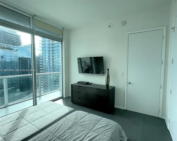 a bedroom with a bed and a flat tv screen on dresser