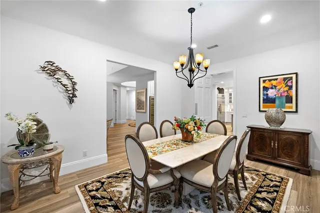 a dining room with chandelier and wooden floor
