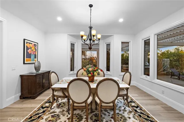 a dining room with chandelier and wooden floor