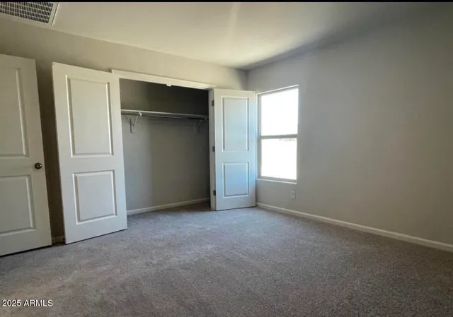 an empty room with closet and windows