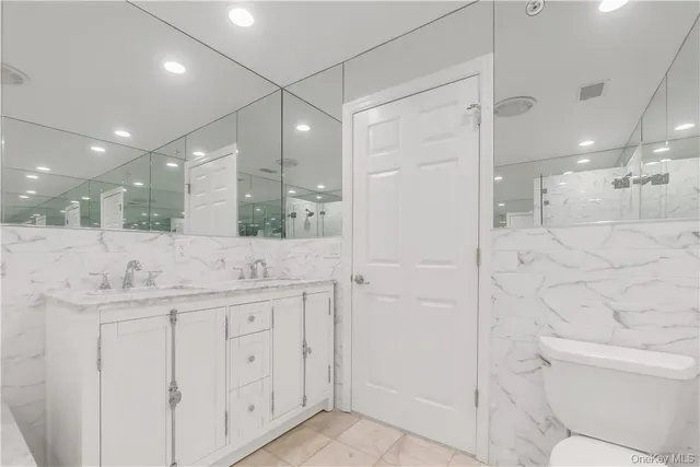 a bathroom with a granite countertop sink a toilet a mirror and shower