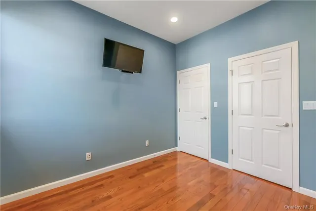 a view of an empty room with wooden floor and a flat screen tv