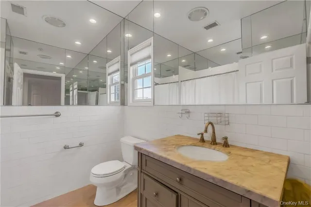 a bathroom with a granite countertop sink a toilet and a mirror