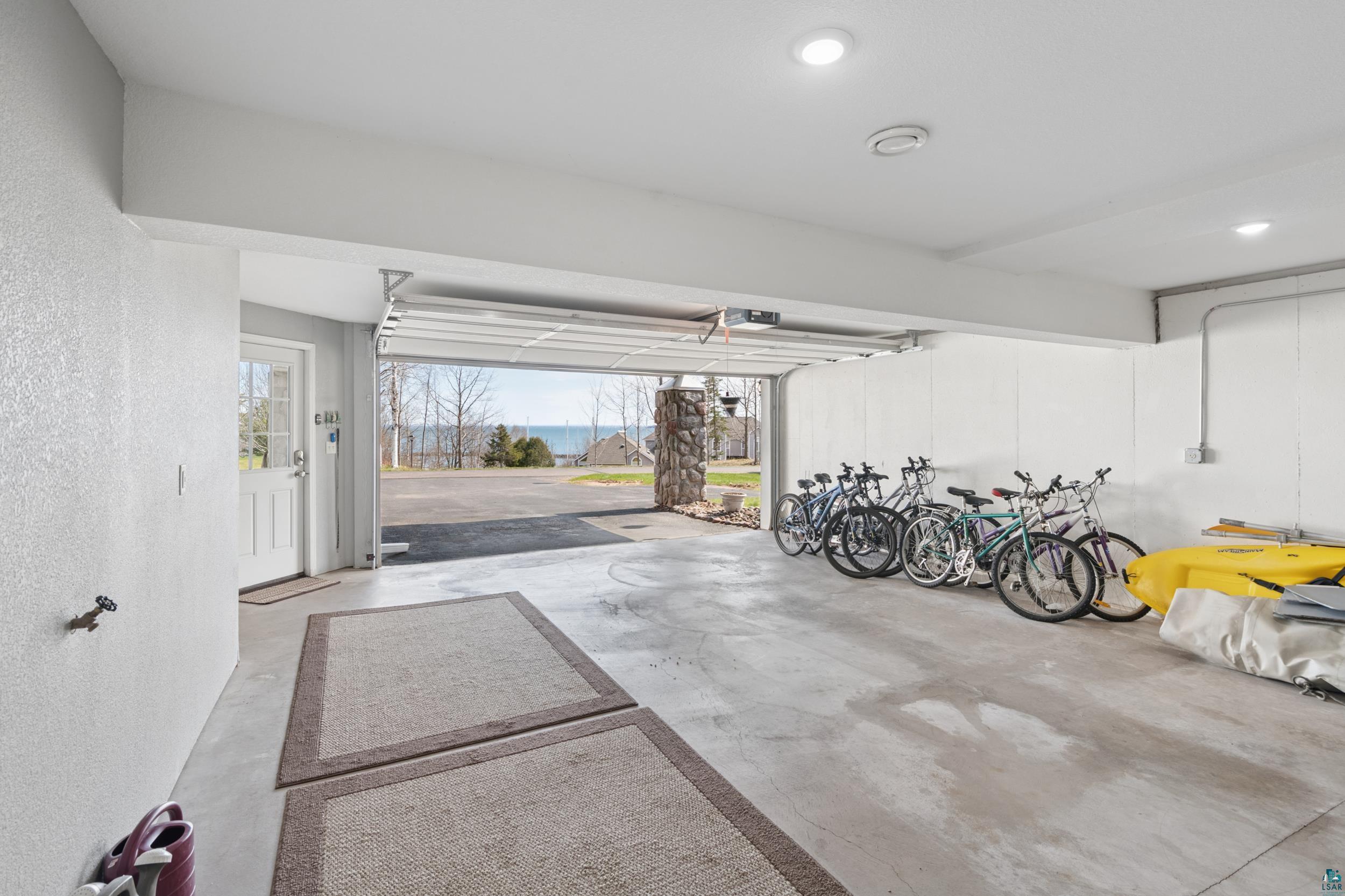 34590 Bay View Road, Unit 801 Bayfield, WI 54814 - Photo 23 of 36 Spacious garage featuring a concrete floor, overhead lighting, an exterior door with window panes, an exposed conduit system, and a stone column exterior accent