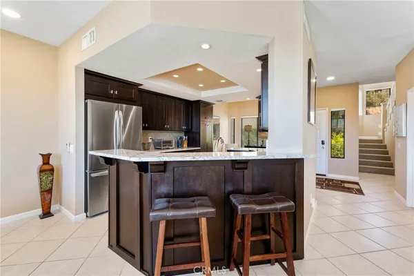 a kitchen with stainless steel appliances kitchen island granite countertop dining table chair and a refrigerator