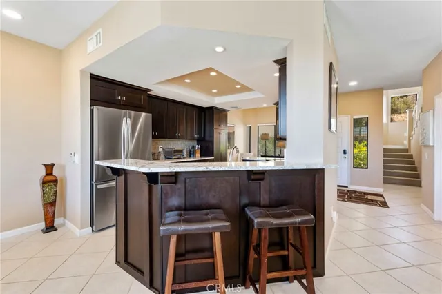 a kitchen with stainless steel appliances kitchen island granite countertop dining table chair and a refrigerator