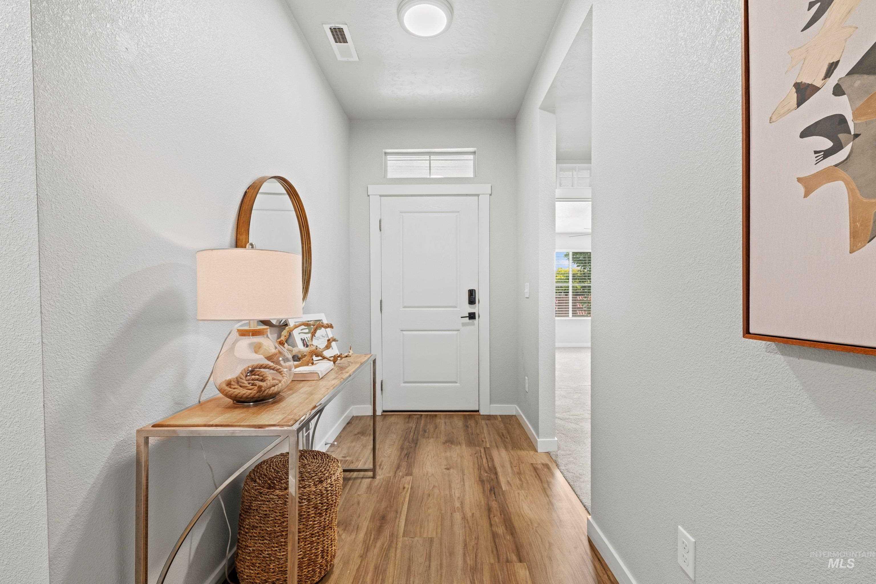 12744 West Fig Street Boise, ID 83713 - Photo 5 of 34 Entryway featuring wood-finish flooring, light gray walls, a white front door, and an overhead transom window