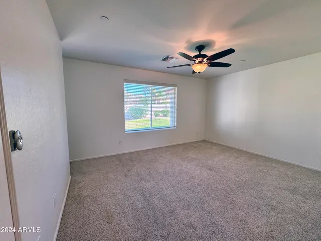 an empty room with windows and ceiling fan