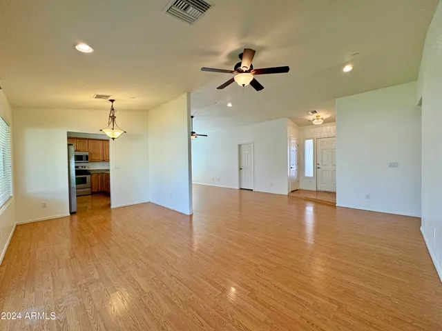 a view of empty room with wooden floor and ceiling fan