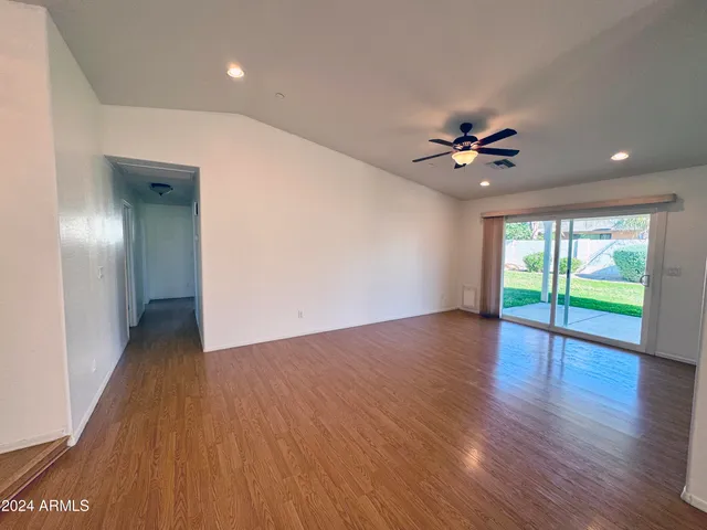 a view of an empty room with window and wooden floor