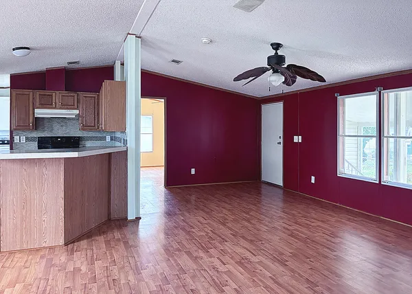a view of an empty room with window and wooden floor