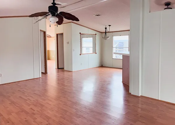 a view of a big room with wooden floor and windows
