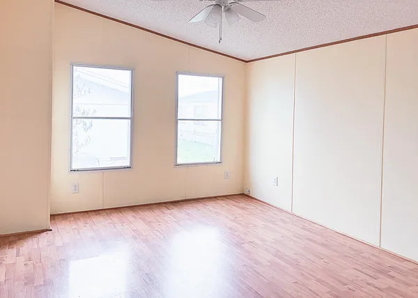a view of an empty room with a ceiling fan and wooden floor
