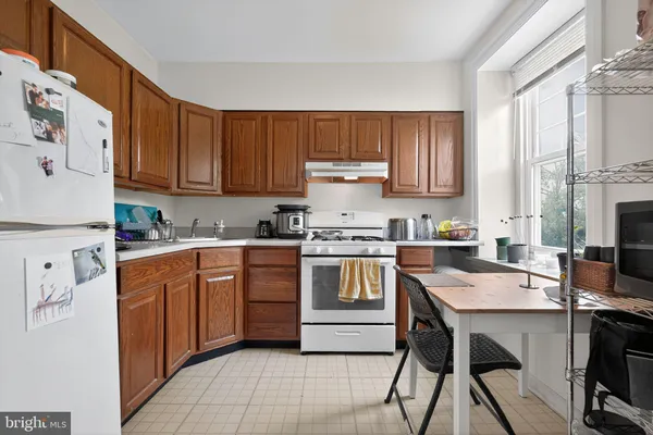 a kitchen with stainless steel appliances granite countertop a stove a sink dishwasher and a refrigerator with wooden cabinets