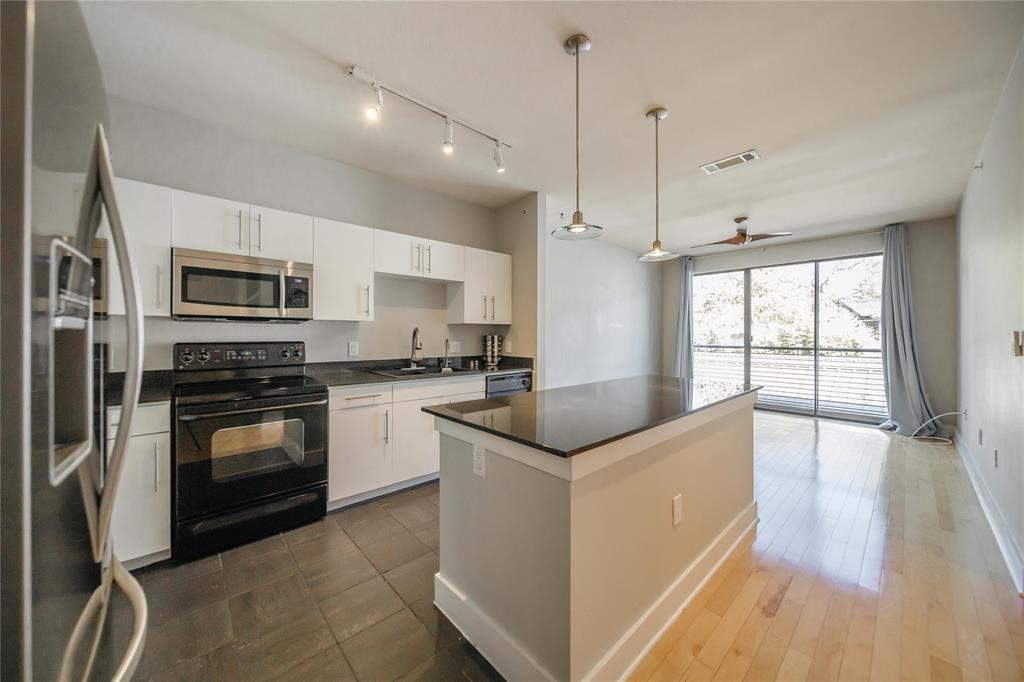 4414 Cedar Springs Road, Unit 214 Dallas, TX 75219 - Photo 5 of 29 Kitchen featuring black appliances, white cabinetry, a kitchen island, and decorative light fixtures