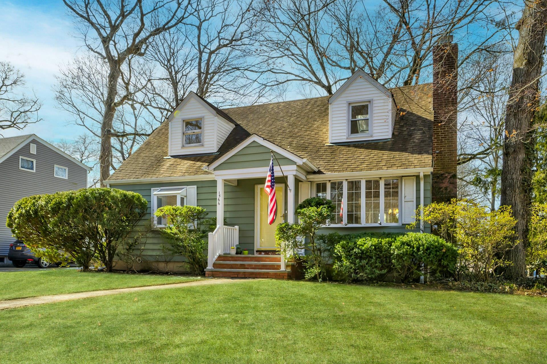 1566 Middle Neck Road Port Washington, NY 11050 - Photo 1 of 1 Cape cod-style house with a shingled roof, a chimney, and a front lawn