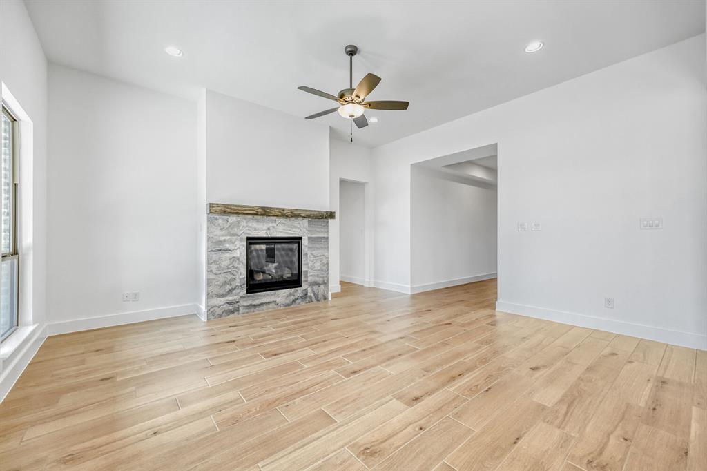 147 Derrett Lane Rhome, TX 76078 - Photo 4 of 28 Unfurnished living room with a ceiling fan, recessed lighting, light wood-type flooring, and a fireplace