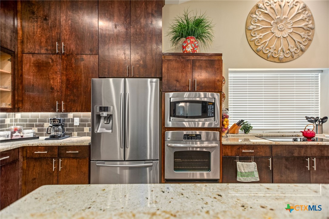 265 Coastal Oaks Loop Port O'Connor, TX 77982 - Photo 46 of 48 a kitchen with stainless steel appliances kitchen island granite countertop a refrigerator and a stove top oven