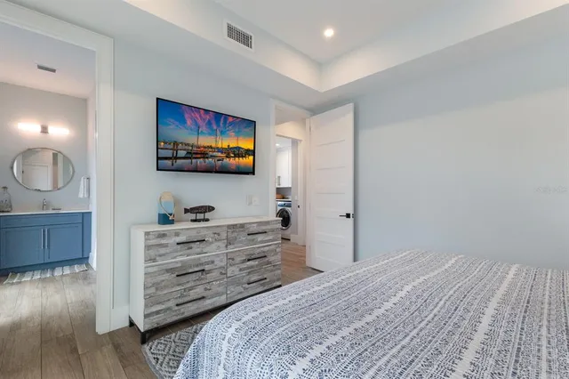 a bedroom with a large bed a flat tv screen and dresser