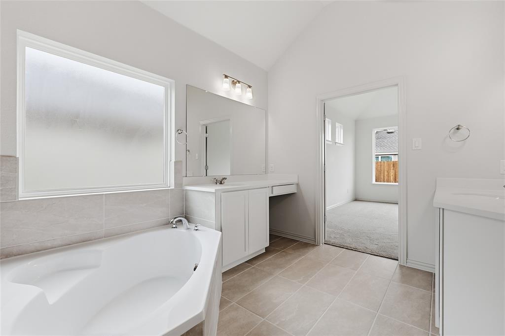 3737 Pitchfork Terrace Anna, TX 75409 - Photo 17 of 33 Contemporary bathroom featuring a built-in soaking tub with tile surround, a large frosted window, dual white vanities with integrated sinks, and neutral tile flooring