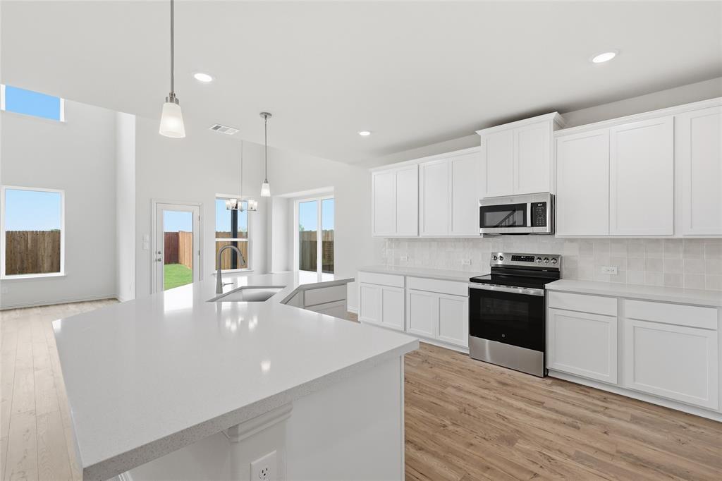 3737 Pitchfork Terrace Anna, TX 75409 - Photo 6 of 33 Open-concept kitchen featuring an expansive island with a sink, white cabinetry, a subway tile backsplash, and stainless steel appliances