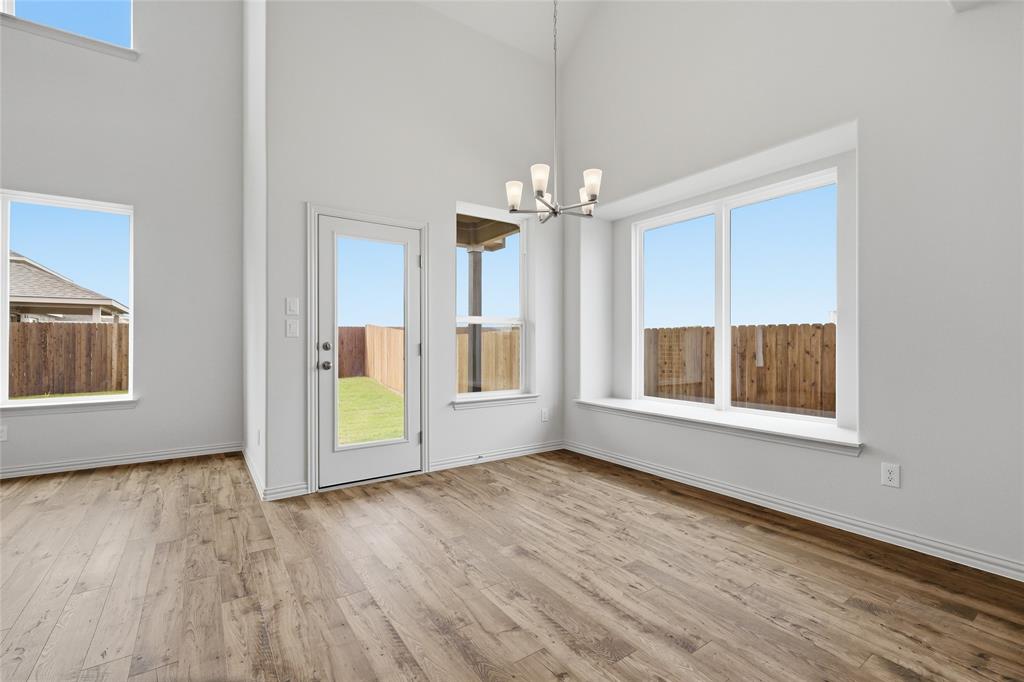 3737 Pitchfork Terrace Anna, TX 75409 - Photo 9 of 33 Spacious room with high ceilings, wood-finish flooring, multiple large windows, a glass-paneled door, and a contemporary chandelier