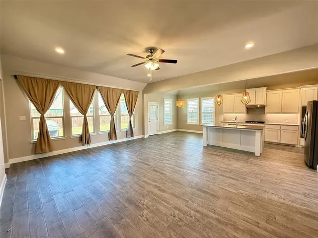 a view of an empty room with a kitchen and wooden floor