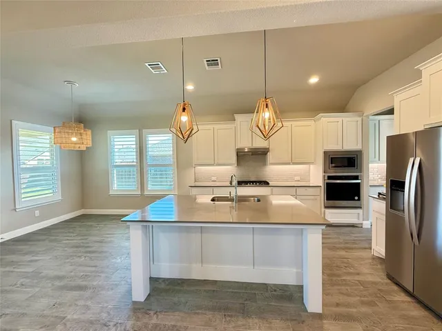 a kitchen with kitchen island a sink appliances and cabinets