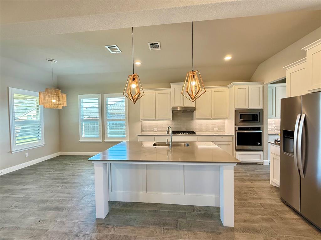 3476 Evergreen Way Midlothian, TX 76065 - Photo 6 of 22 Kitchen featuring appliances with stainless steel finishes, hanging light fixtures, decorative backsplash, an island with sink, and white cabinets