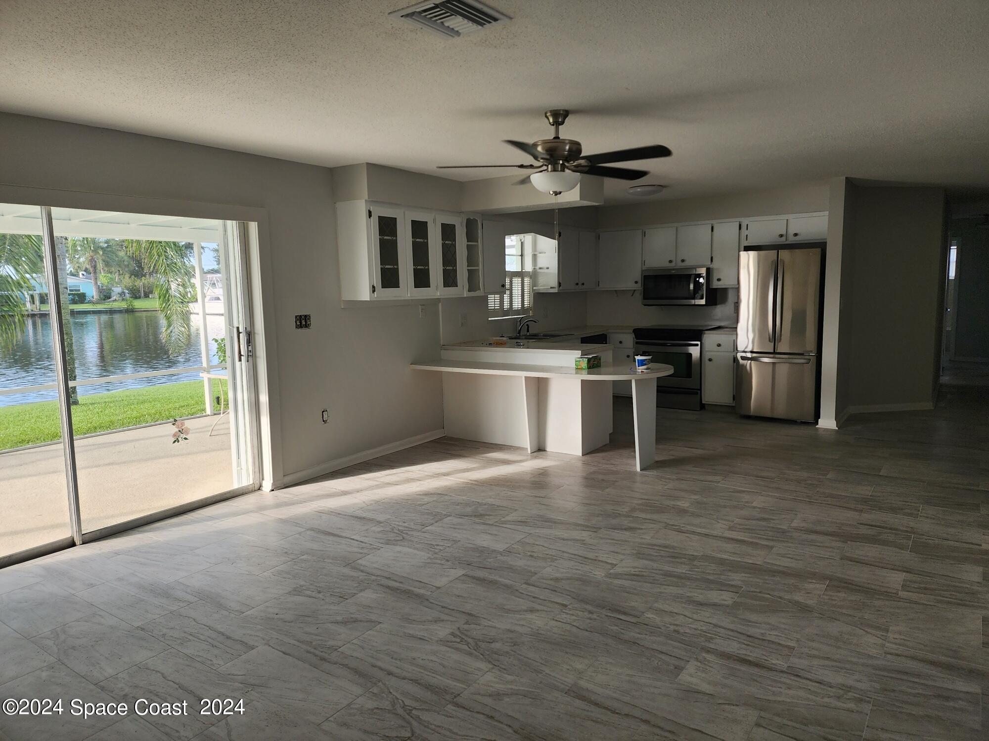 1725 Reef Court Merritt Island, FL 32952 - Photo 5 of 26 a view of a kitchen with a sink a refrigerator a ceiling fan and wooden floor