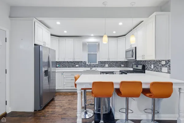a kitchen with stainless steel appliances kitchen island granite countertop a table chairs and a refrigerator
