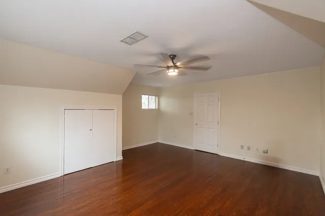 an empty room with wooden floor chandelier fan and windows