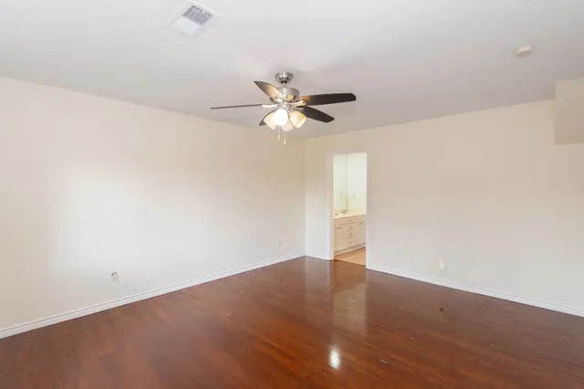 a view of an empty room with a ceiling fan and wooden floor