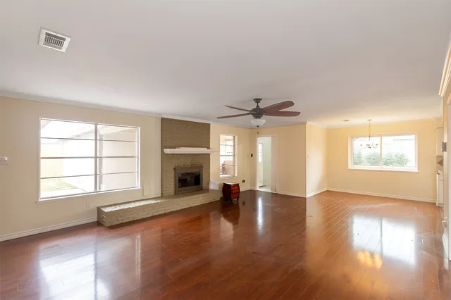 an empty room with fireplace wooden floor and windows