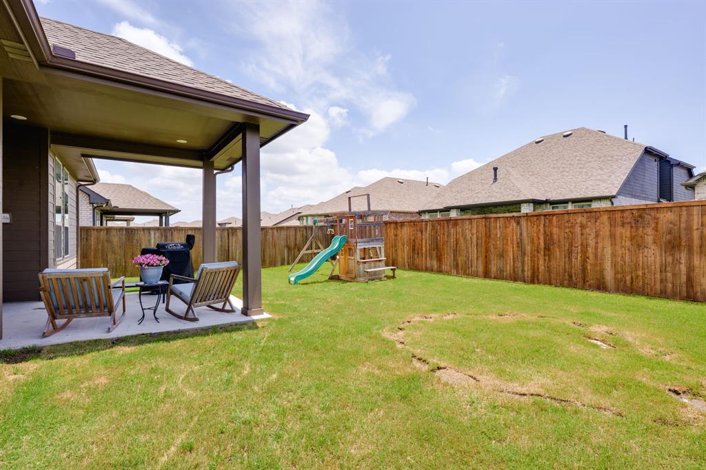 1320 Rosebush Road Aubrey, TX 76227 - Photo 27 of 33 a view of a backyard with table and chairs under an umbrella