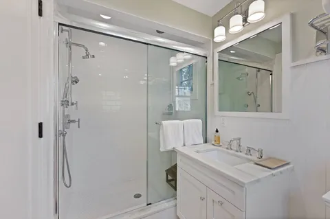 a bathroom with a shower sink vanity and mirror