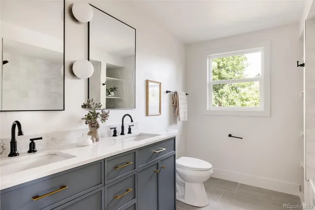 a bathroom with a toilet a sink a mirror a window and vanity