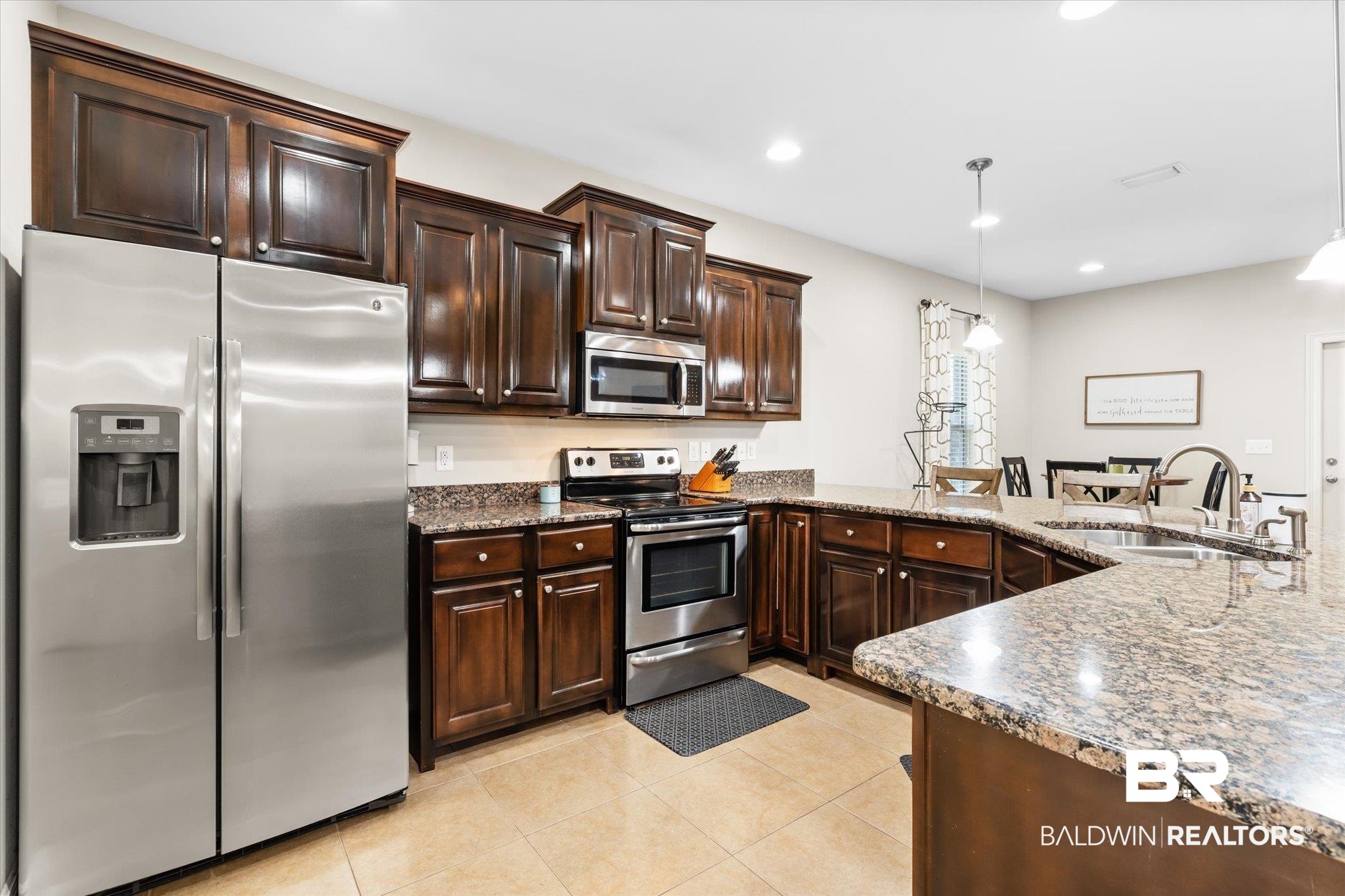22640 Nana Loop East Silverhill, AL 36576 - Photo 5 of 46 Kitchen with dark brown cabinets, sink, decorative light fixtures, light tile patterned floors, and appliances with stainless steel finishes