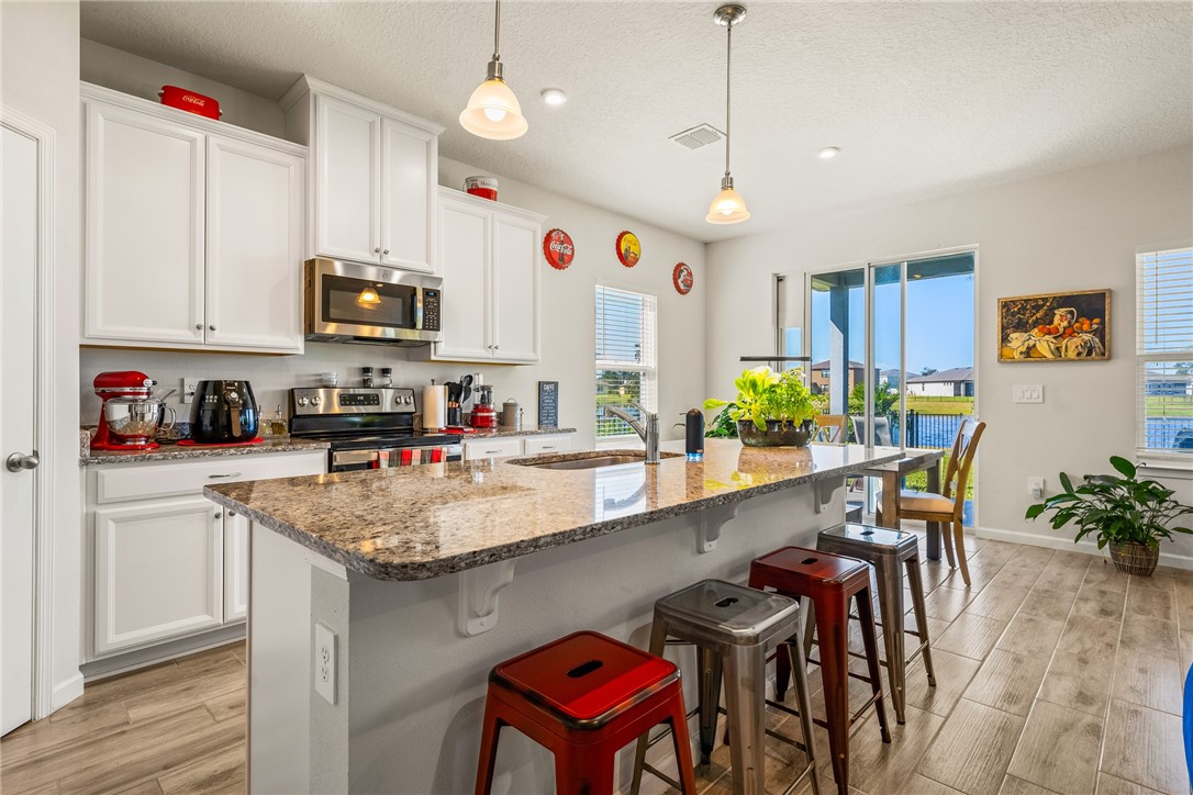 4202 Keeson Circle Vero Beach, FL 32967 - Photo 3 of 36 a kitchen with stainless steel appliances granite countertop a kitchen island a stove a table and chairs in it