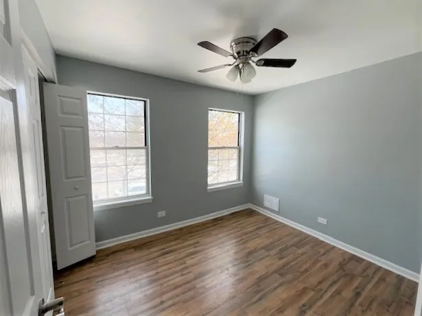 a view of empty room with wooden floor and fan