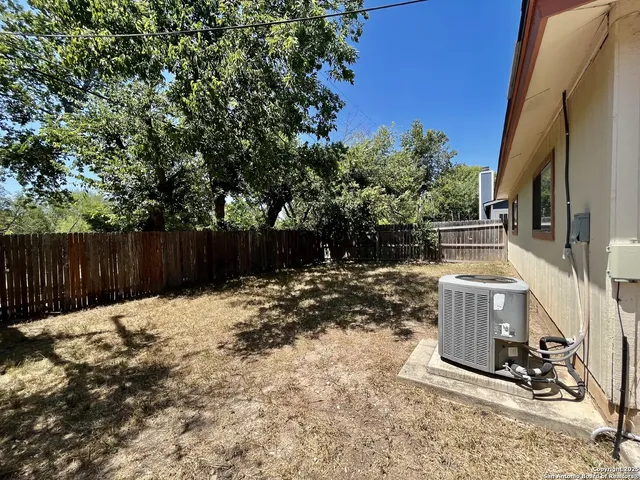 a backyard of a house with wooden fence and trees